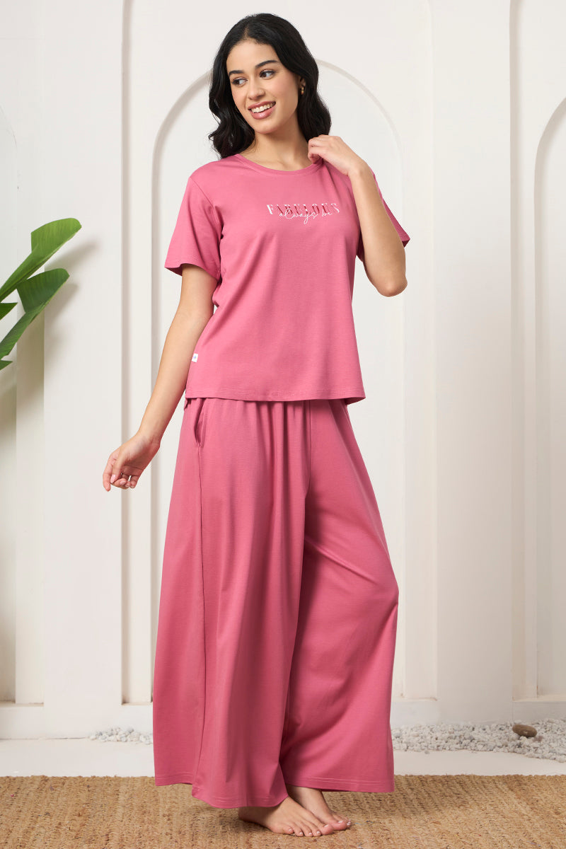 Woman smiling sideways in a pink t-shirt and wide leg pants co-ord set
