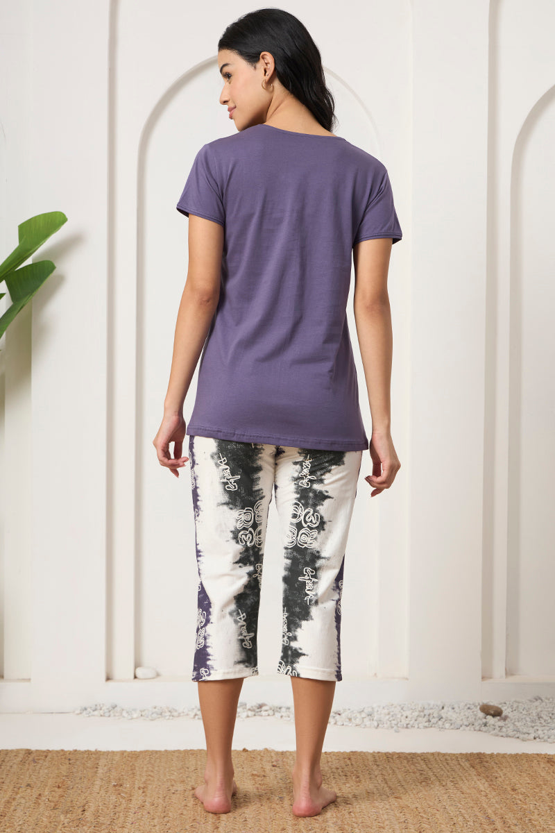 Back view of a woman wearing a purple tee and printed capris