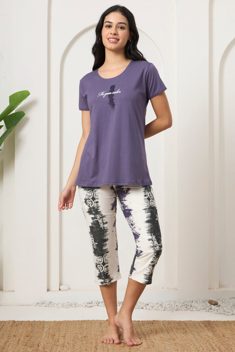 Woman smiling in a purple graphic tee with printed capri pants