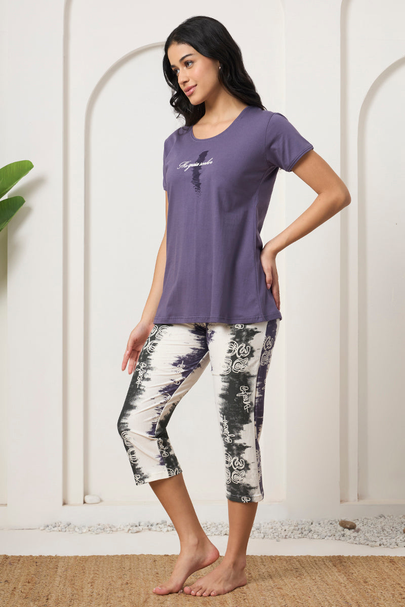 Woman in a purple tee and printed capri pants, side view