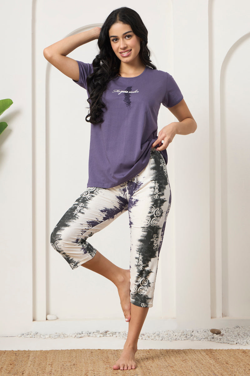 Woman posing in a purple graphic tee with printed capris