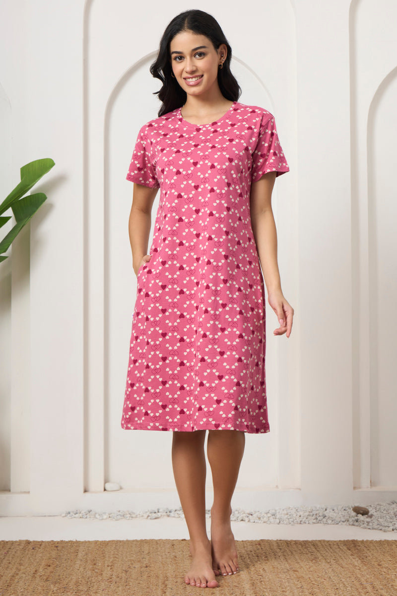 Woman standing in a pink heart print nightdress with pockets