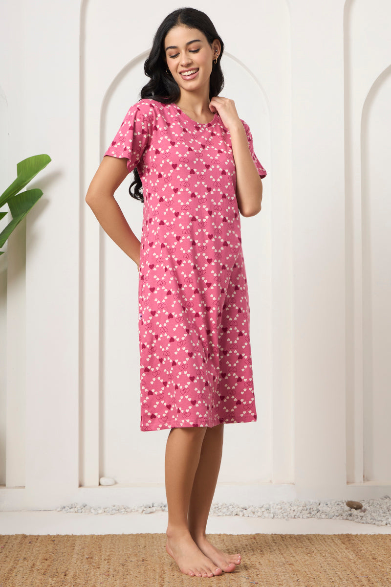 Woman smiling with hand on hip in a pink heart print nightdress