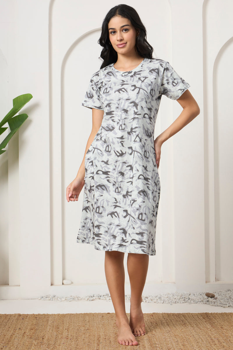 Woman standing in a grey abstract print nightdress with pockets