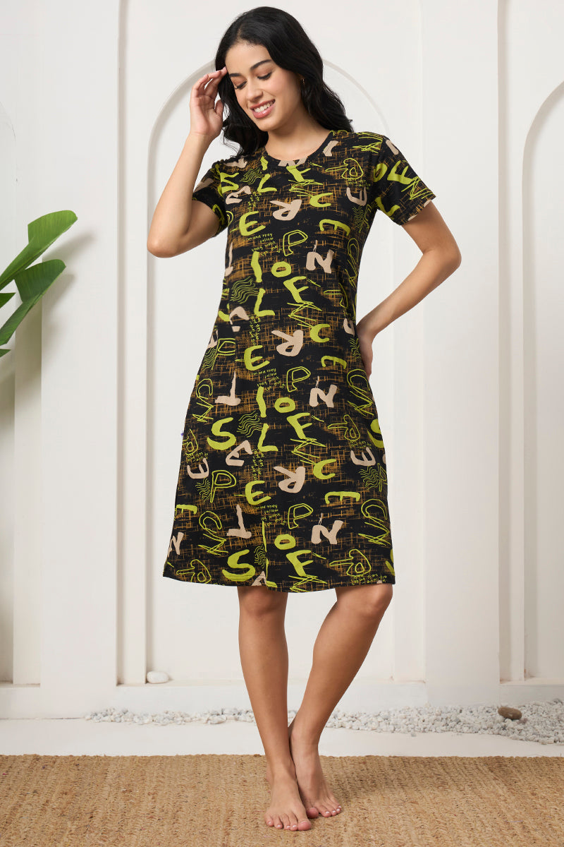 Woman smiling with hand on hip in a black and green print nightdress