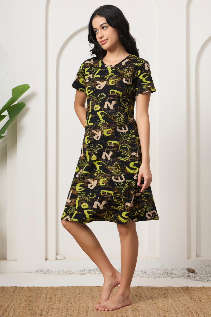 Woman standing sideways in a black and green typographic print nightdress