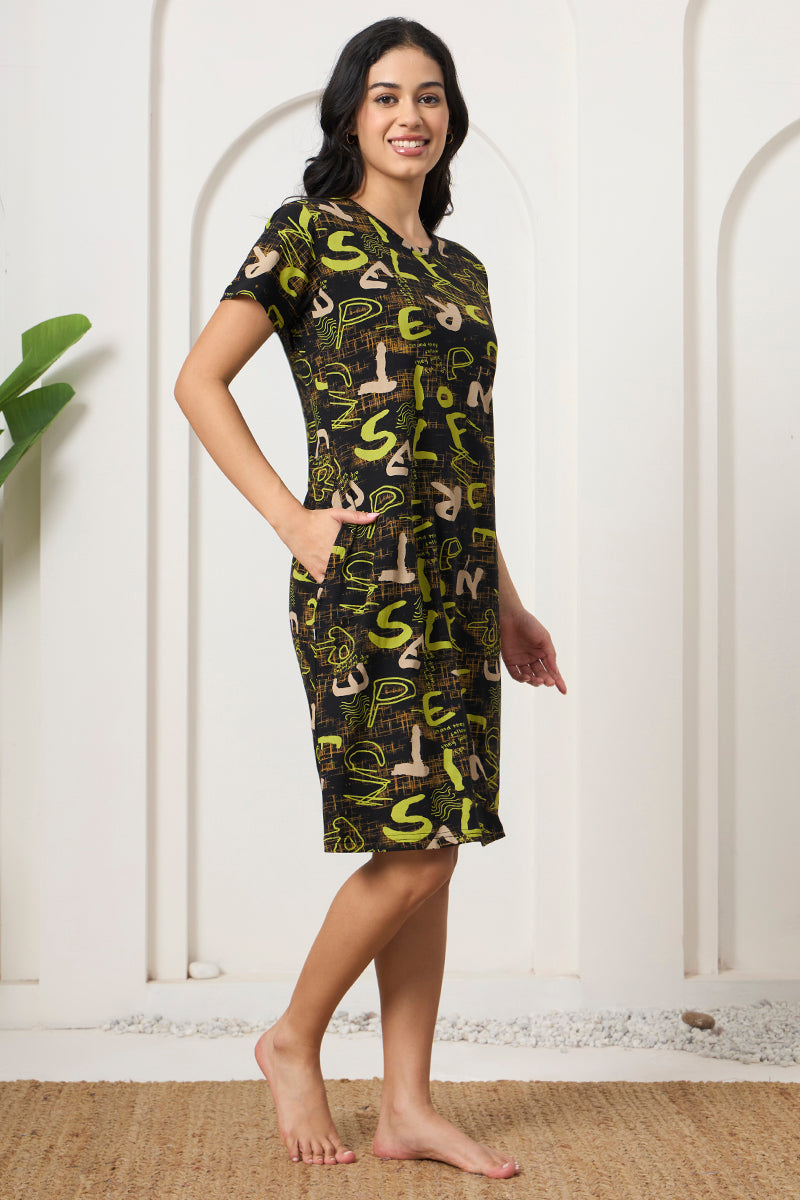 Woman standing sideways in a black and green print nightdress with pockets