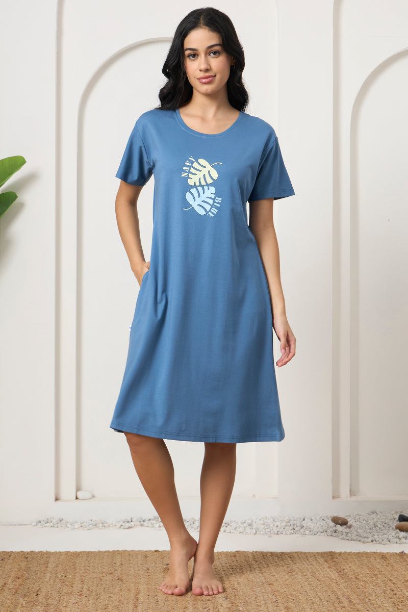 Woman smiling in a blue leaf print short sleeve nightdress with pockets