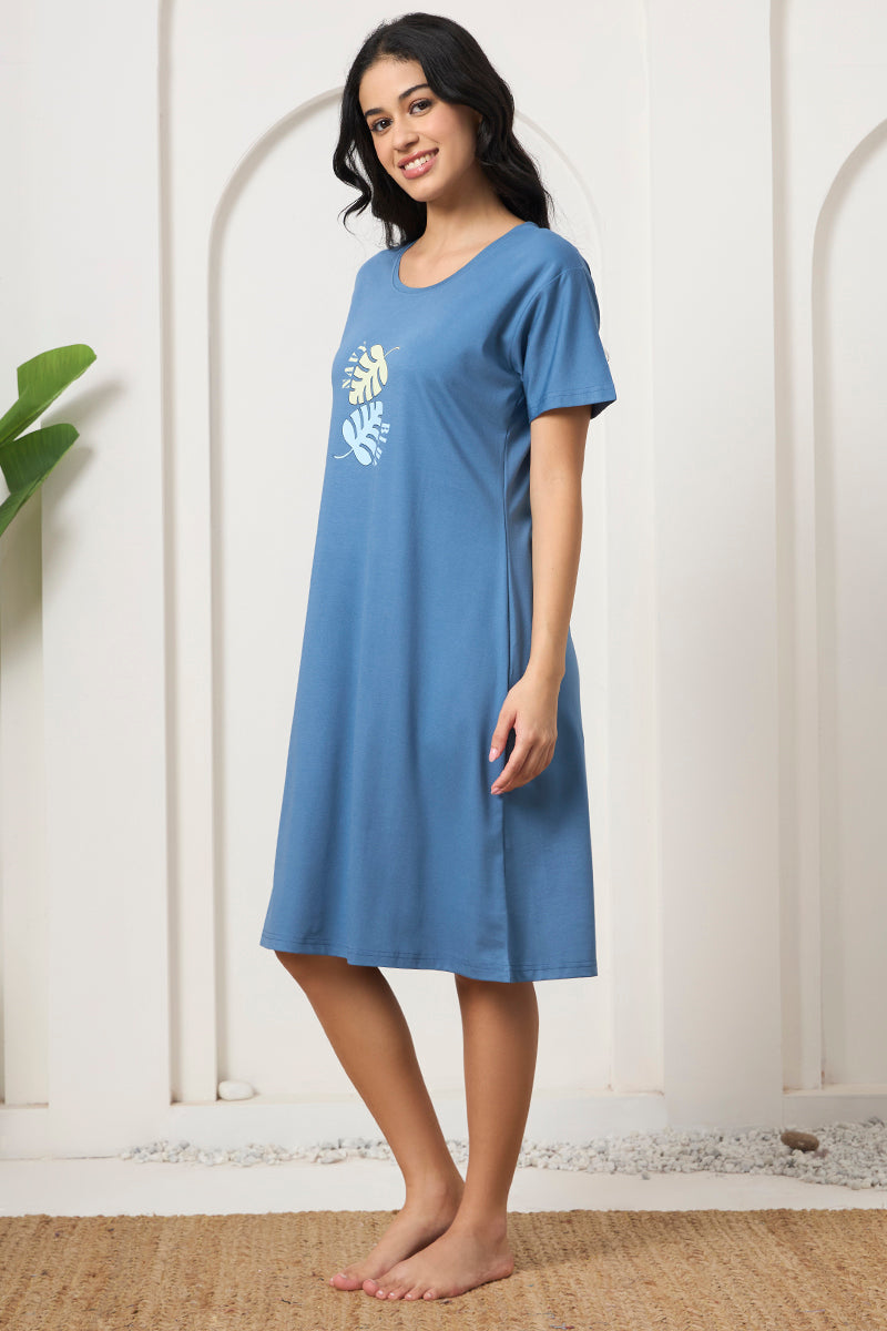 Woman standing sideways in a blue leaf print t-shirt style nightdress