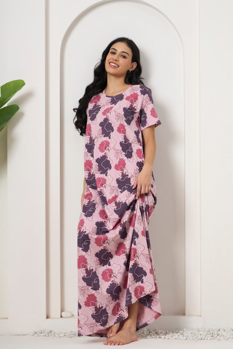 Woman posing against a wall in a pink and purple floral print nightdress
