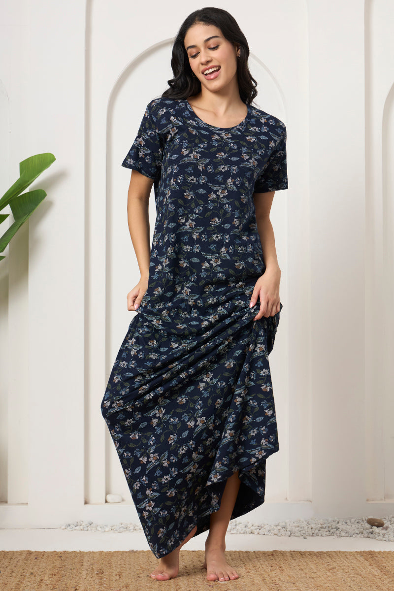 Woman swishing the hem of a navy floral print maxi nightdress