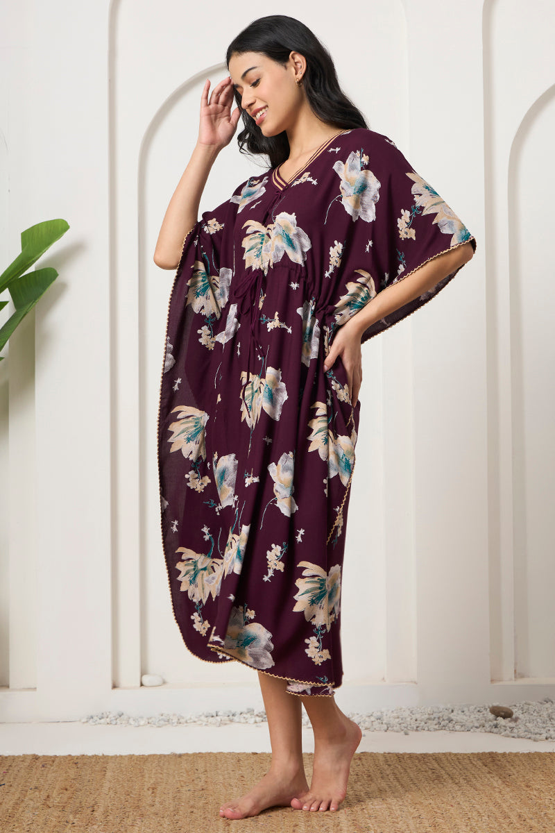 Woman standing sideways in a wine floral print kaftan