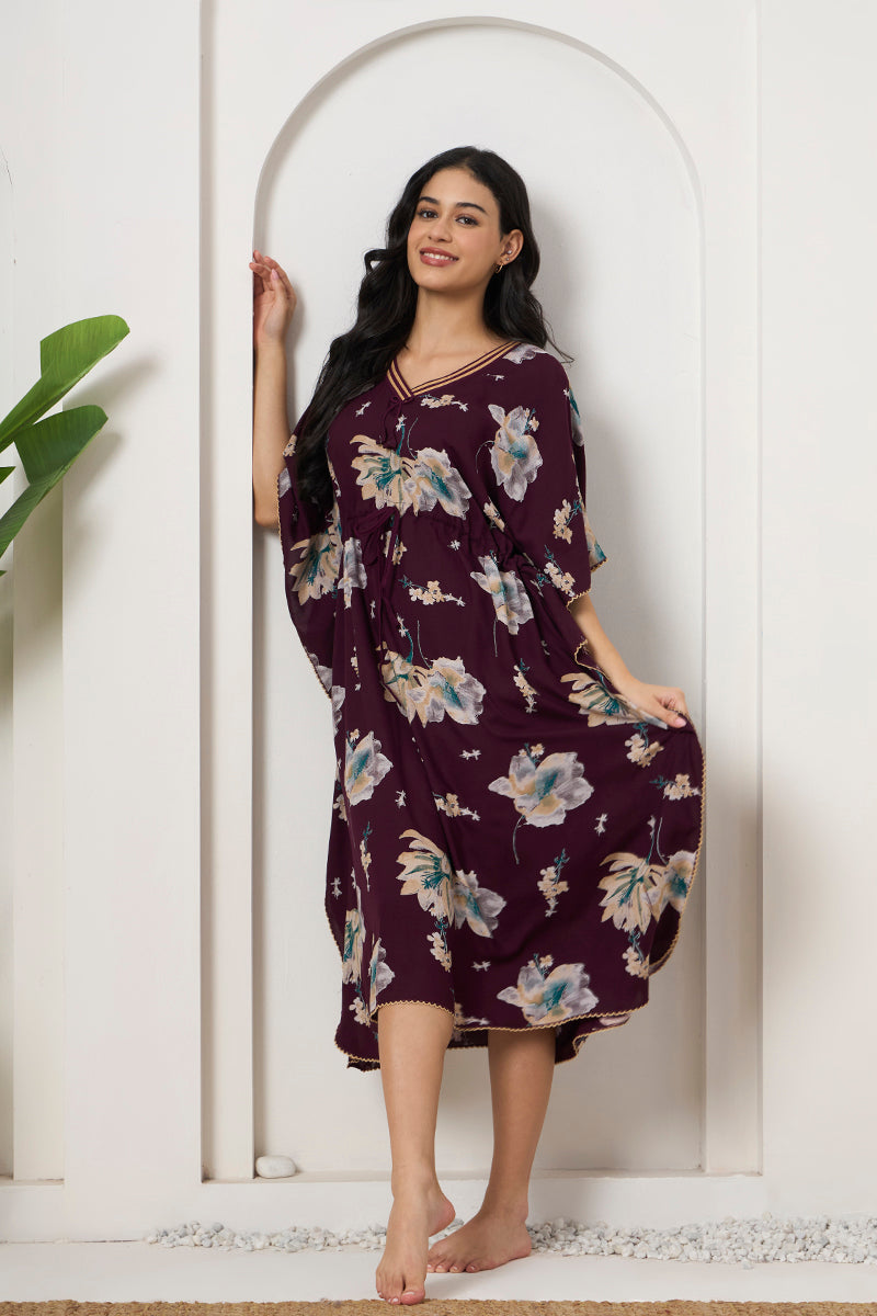 Woman leaning against a wall in a wine floral kaftan