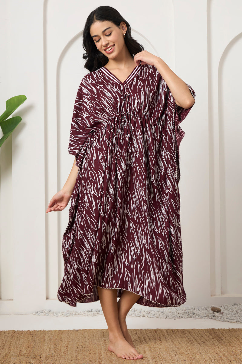 Woman smiling and adjusting the collar of her wine printed kaftan