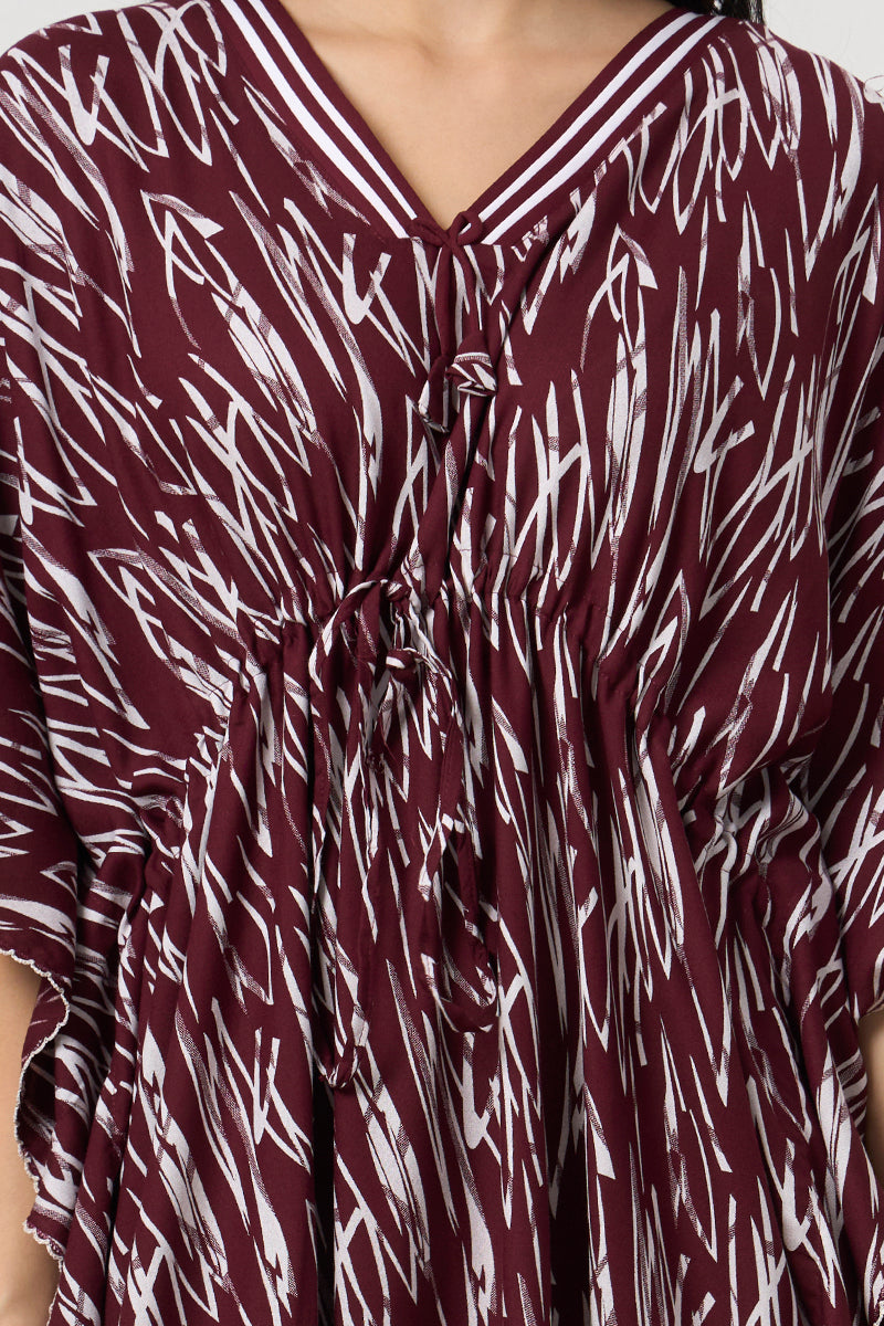 Close up of the tie neck and drawstring waist on the wine kaftan