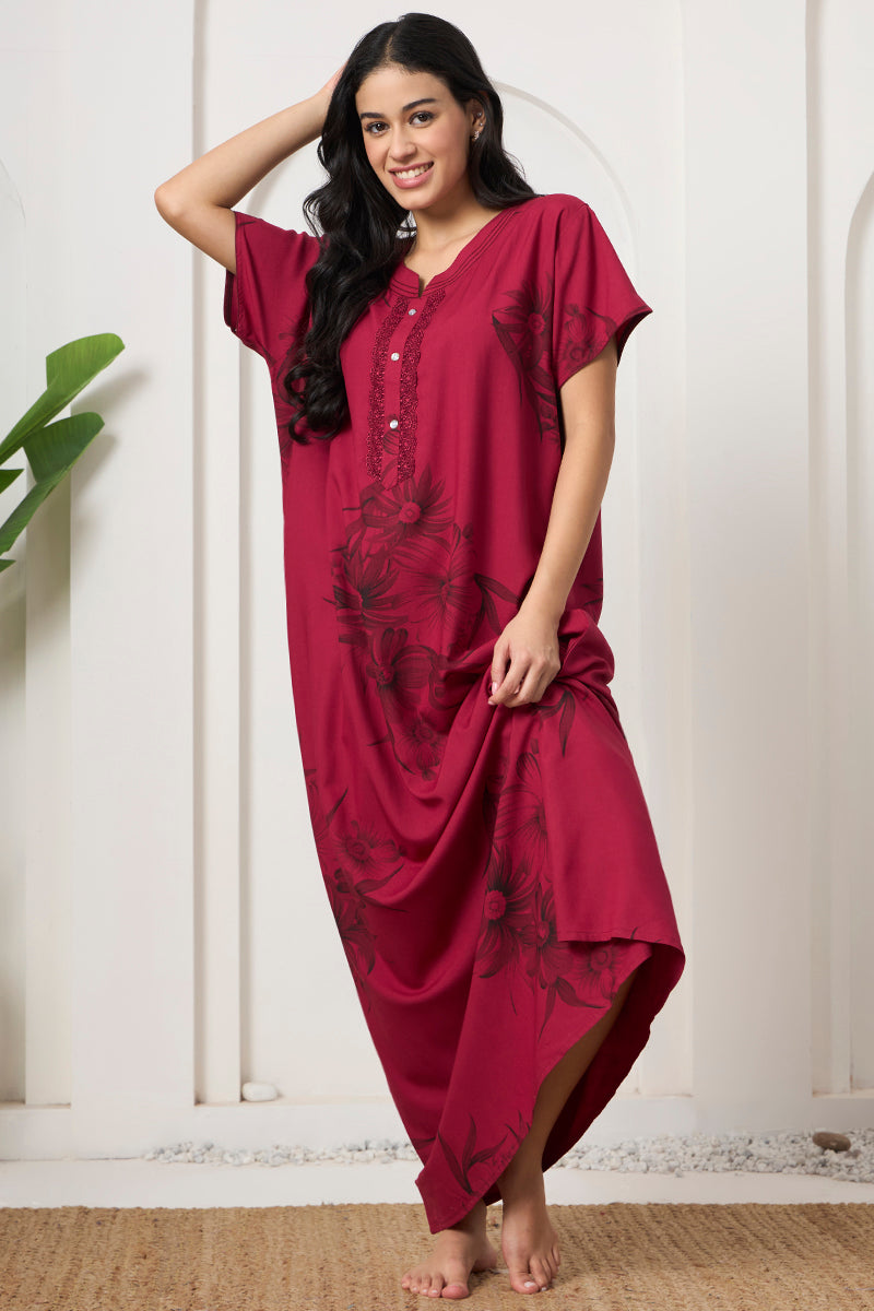 Woman smiling with hand in hair, wearing a maroon printed nightgown